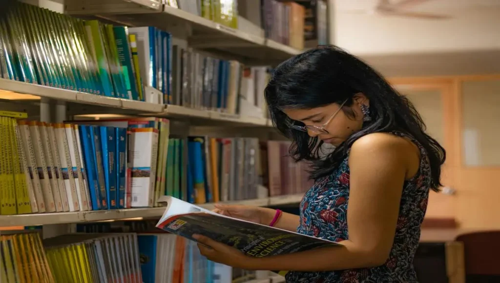 Une fille lisant un livre dans une bibliothèque.